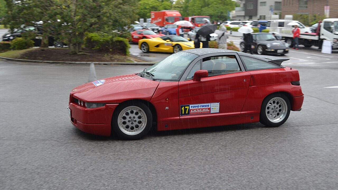 Red Alfa Romeo SZ driving on the road.